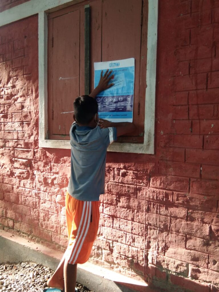 The image shows a child puts up a poster in school premises (wall).